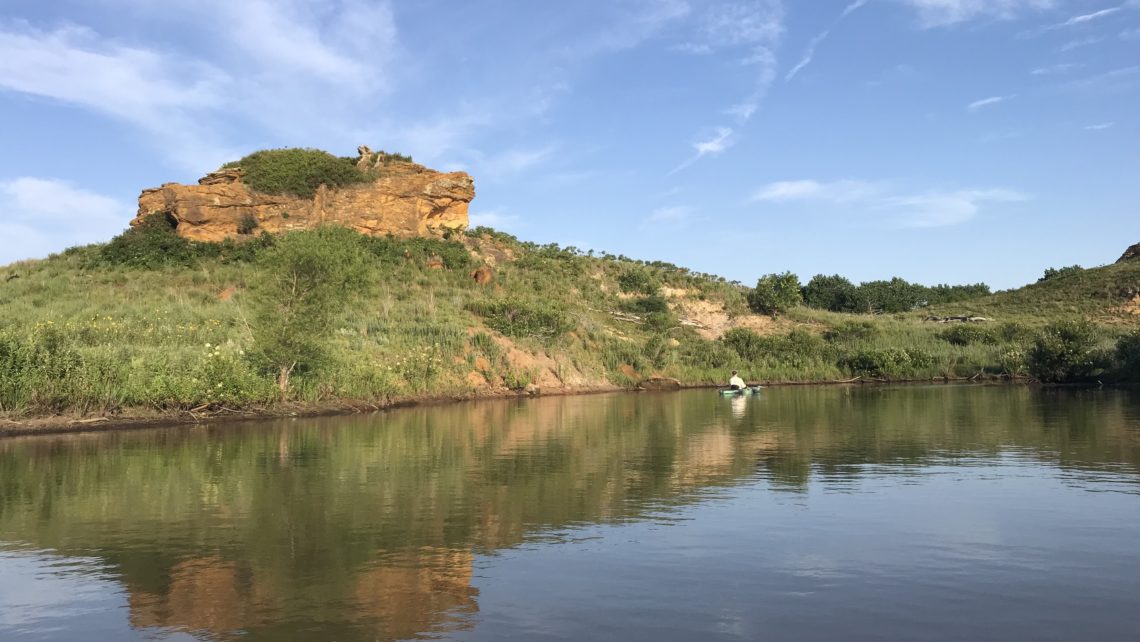 Canoe on Kanopolis Lake, Kansas. Sandstone formation reflected in water.