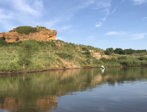 Canoe on Kanopolis Lake, Kansas. Sandstone formation reflected in water.