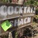 Wooden sign reading "cocktail shack" with sticky note reading "writing shack"