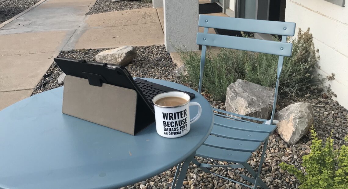 Small table, iPad, and mug that says writer, because badass isn't a job title